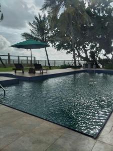 a swimming pool with two chairs and an umbrella at Olivia Bungalow in Wattala