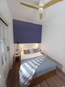 - une chambre dotée d'un lit avec un mur bleu dans l'établissement Una ventana al Mar en Málaga, à Malaga