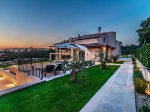 ein Haus mit einer Terrasse und einem Garten mit einer Liegewiese in der Unterkunft Large luxury villa with swimming pool and outdoor kitchen in Svetvinčenat