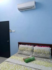 a bed with two pillows and a green bottle on it at Zara Dija Homestay Klia/Klia2 in Sepang