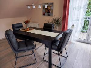 een zwarte eettafel met 4 stoelen en een tafel bij Ferienwohnungen Meindl in Idar-Oberstein
