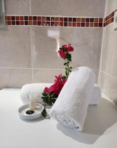 une salle de bain avec deux serviettes et une fleur sur une baignoire dans l'établissement Anse des rochers - Ti Kaz MiLouMa, à Saint-François