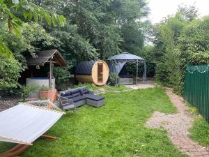 een achtertuin met een hangmat en een prieel bij Ferien-Villa direkt am Rhein Sauna/Whirlpool in Götterswickerhamm
