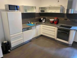 a kitchen with white cabinets and a white refrigerator at Ferien-Villa direkt am Rhein Sauna/Whirlpool in Götterswickerhamm