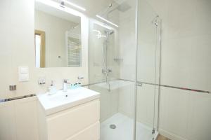 a white bathroom with a sink and a shower at Apartimento Angel River 7 in Wrocław