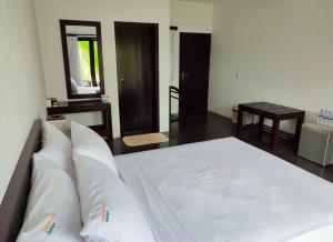 uma cama com lençóis brancos e almofadas num quarto em Lakmini Lodge Sigiriya em Sigiriya