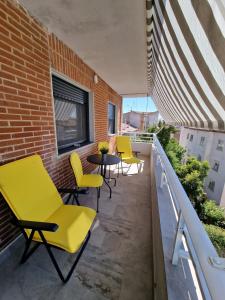 um pátio no último piso com cadeiras amarelas e uma mesa em Aurora em Ávila