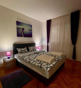 a bedroom with a large bed with two lamps at Apartman Venera in Sombor