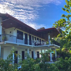 a white building with a balcony and trees at Hotel Siyathma polonnaruwa in Polonnaruwa