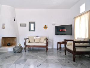 a living room with a couch and a tv at Amelie Villa with pool and amazing sea views, Paros in Márpissa