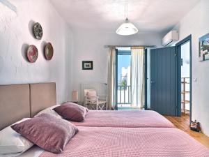 a bedroom with two beds with pink sheets at Amelie Villa with pool and amazing sea views, Paros in Márpissa