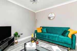 a living room with a green couch and a tv at Birmingham Near Airports & NEC, Contractors & Leisure Stays Property Retreat Short Lets & Serviced Accommodation in Kingshurst