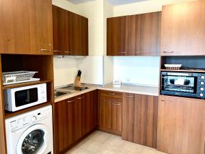 a kitchen with wooden cabinets and a washer and dryer at Private Suite at Comfort Bansko in Bansko