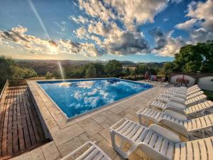 a swimming pool with white lounge chairs next to it at Conacul lui Bulică in Novaci-Străini