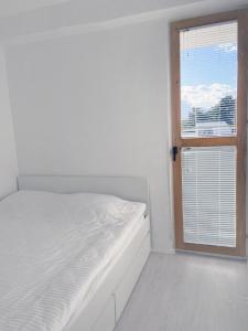 a white bedroom with a bed and a window at Apartment in Vitina