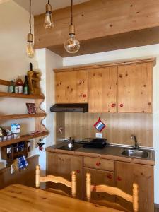 uma cozinha com armários de madeira, um lavatório e uma mesa em IL COVO DELLO SCIATORE em Falcade