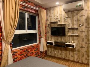 a bedroom with a brick wall with a tv and a window at Homestay 9view thủ Đức in Ho Chi Minh City