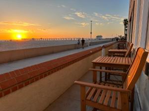 einen Sonnenuntergang am Strand mit zwei Tischen und Bänken in der Unterkunft The Vurpillat in Hermosa Beach