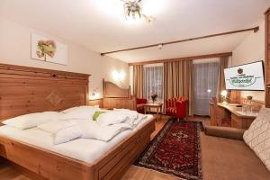 a bedroom with a large bed and a living room at Familien- und Vitalhotel Mühlpointhof in Lofer +48 photos