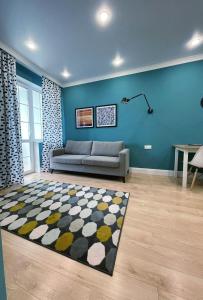 uma sala de estar com um sofá e uma parede azul em Appartment- Sauran 15 near the Garden em Astana