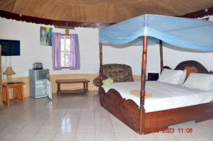 a bedroom with a canopy bed and a tv at Easy Time Lodge in Kololi