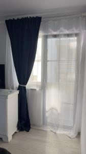 a window with a blue curtain in a room at Apartament Craiova Magnolia in Craiova