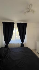 a bedroom with a black bed and a window at Apartament Craiova Magnolia in Craiova