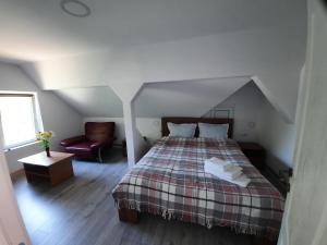 a bedroom with a bed and a chair in a attic at Casa Maia in Cîrţişoara