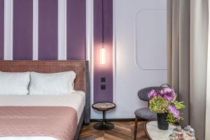 um quarto com uma cama e uma cadeira e riscas roxas em Eitch Belsiana Relais em Roma