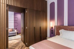 ローマにあるEitch Belsiana Relaisの紫の壁のベッドルーム1室、ベッド1台、ソファが備わります。