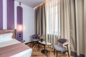 ローマにあるEitch Belsiana Relaisのベッド1台、椅子2脚、テーブルが備わる客室です。