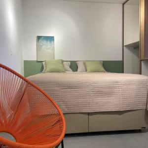a bedroom with a bed and a orange chair at Seu Canto no Mar do Campeche in Florianópolis
