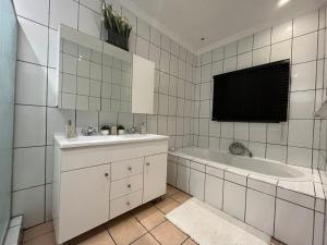 a white bathroom with a tub and a sink and a bath tubermott at Kiwi Boutique Lodges in Pretoria