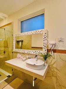 W łazience znajduje się umywalka i lustro. w obiekcie Yog Niketan Villa w mieście Rishikesh