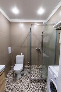 uma casa de banho com um WC e uma cabina de duche em vidro. em Appartment- Sauran 15 near the Garden em Astana
