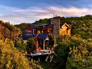 Homestay at "Explore Cafe & Lodge" with stunning ocean view in Chiloe Island, Patagonia في Duhatao: منزل كبير على قمة تل به أشجار