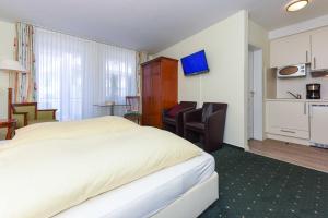 a hotel room with a large bed and a kitchen at Apartments im Nordseegartenpark in Bensersiel