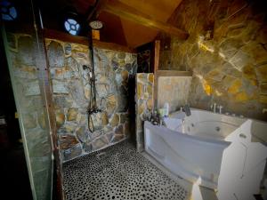 Homestay at "Explore Cafe & Lodge" with stunning ocean view in Chiloe Island, Patagonia في Duhatao: حمام مع حوض استحمام وجدار حجري