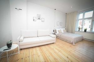 a white living room with a couch and a bed at Apartament Haffnera in Sopot