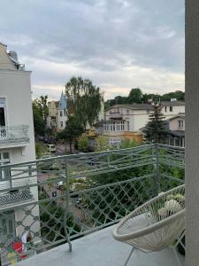 a chair on a balcony with a view of a city at Apartament Haffnera in Sopot