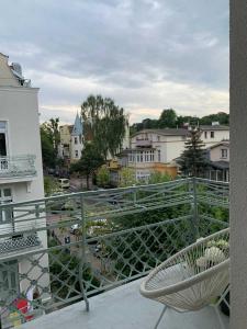 Una silla en un balcón con vista a una ciudad. en Apartament Haffnera, en Sopot