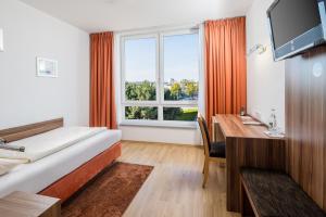 Habitación de hotel con cama, escritorio y ventana en Hotel Meridian ***superior, en Landshut