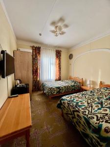 a hotel room with two beds and a table at Arabon Hotel in Bukhara