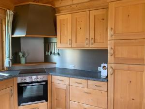 La cuisine est équipée de placards en bois et d'un four avec plaques de cuisson. dans l'établissement Chalet Leitn-Anger, à San Leonardo in Passiria