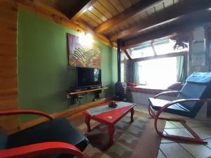 a living room with chairs and a table and a tv at Cabañas con costa al lago, Kalfulafquen in Villa La Angostura