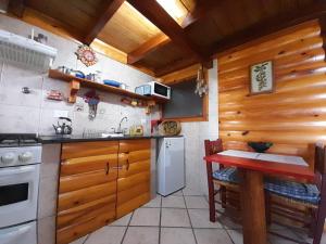 a kitchen with wooden cabinets and a red table in it at Cabañas con costa al lago, Kalfulafquen in Villa La Angostura