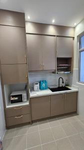 a kitchen with brown cabinets and a sink and a microwave at SYG12 Homestay Dalur Presint 18 in Putrajaya