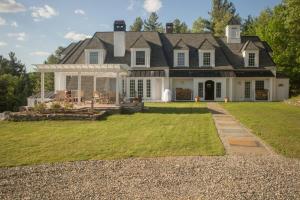 une grande maison blanche avec une terrasse couverte et une pelouse dans l'établissement Adams Hill House Retreat - Artist-Architect's Estate, Newfane Vermont, à Newfane
