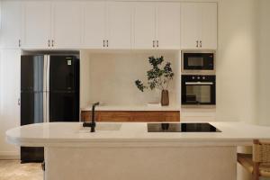 a kitchen with white cabinets and a black refrigerator at BeLam in Hue Villa in Hue