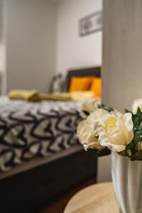 un jarrón con rosas blancas sobre una mesa con una cama en Apartman Georgijev, en Zlatibor